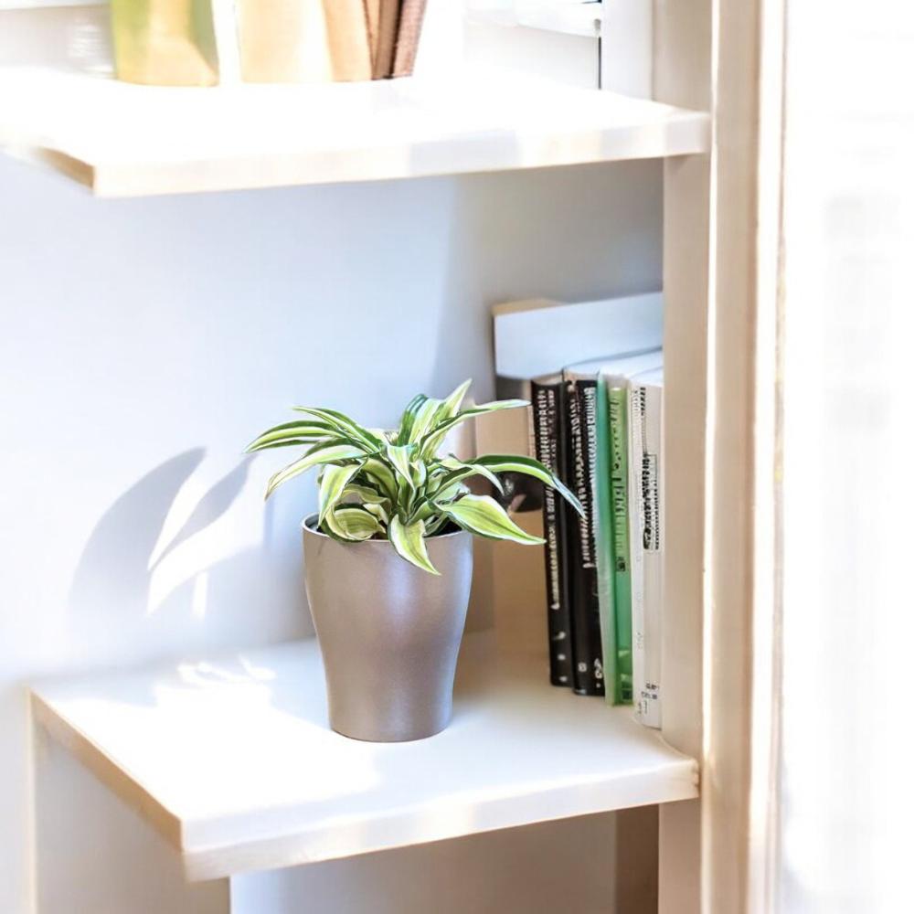 Modern metallic self-watering planter with plant – stylish decor on white bookshelf next to books